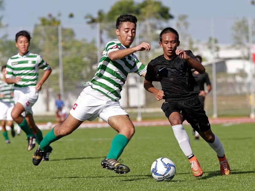 Two school footballers challenging for the ball